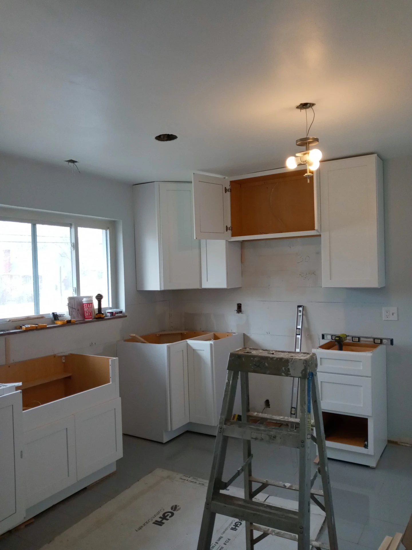 White kitchen cabinets being installed during a remodel